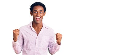 African handsome man wearing casual pink shirt celebrating surprised and amazed for success with arms raised and open eyes. winner concept. 