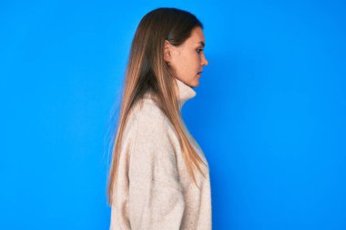 Tüylü, kışlık kazak giyen güzel, beyaz bir kadın. Taraf arıyor, profil pozu veriyor, doğal bir yüzü ve kendine güvenen bir gülümsemesi var.. 