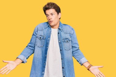 Sıradan bir kot ceket giyen yakışıklı ve elleri havada, kafası karışmış beyaz bir adam. şüphe kavramı. 