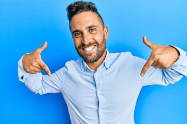 Sakallı, sıradan kıyafetler giyen, kendine güvenen, kendini gururlu ve mutlu gösteren yakışıklı bir adam.. 