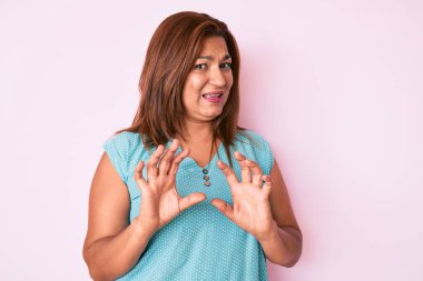 Orta yaşlı esmer kadın, günlük kıyafetler giyen, tiksindirici ve tiksindirici bir ifade takınan, tiksinti reaksiyonu yüzünden tiksindirici bir ifade takınan. Eller havada. 