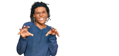 Genç Afro-Amerikan adam günlük kazak giyiyor komik gülüyor kedi gibi pençe hareketi yapıyor, agresif ve seksi bir ifade. 