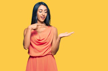 Yazlık elbise giyen güzel İspanyol kadın kameraya hayret ediyor ve gülümsüyor.. 