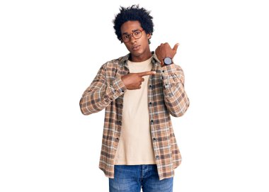 Afro saçlı, sıradan giyinmiş ve gözlüklü yakışıklı Afro-Amerikalı adam. Saati, sabırsızlığı ve rahat bir ifadeyle kameraya bakıyor. 
