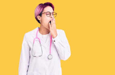 Pembe saçlı, doktor üniforması giyen genç ve güzel bir kadın ağızdan ağıza esnemekten sıkılmış. Huzursuz ve uykulu.. 