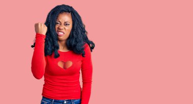 Güzel afro-amerikan kadın rahat kıyafetler giyiyor kızgın ve kızgın yumruğunu kaldırıyor ve öfkeyle bağırıyor. öfke ve agresif konsept. 