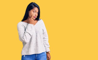 Uzun saçlı İspanyol kadın, sıradan kıyafetler giyiyor. Gözünü dikip jestini izliyor. Şüpheli bir ifade. 