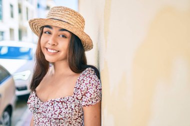 Tatildeki genç Latin kadın gülümsüyor. Şehrin duvarına yaslanmaktan mutlu..