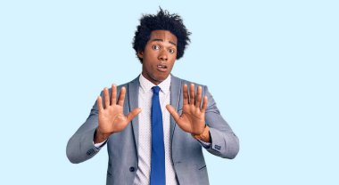 Afro saçlı, iş ceketi giyen yakışıklı Afro-Amerikan erkeği. Avuçlarını hareket ettiriyor, reddediyor ve iğrenç bir ifadeyle reddediyor. Dur ve yasakla. 
