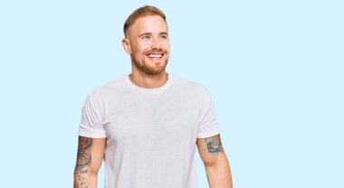 Sıradan kıyafetler giyen genç İrlandalı adam yüzünde gülümsemeyle yan yana bakıyor, doğal bir ifade. Kendinden emin gülen. 