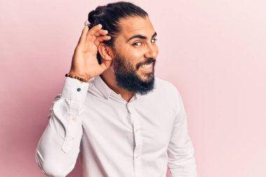 Gündelik giysiler giymiş genç bir Arap, kulağı kulağında gülümsüyor ve dedikoduları dinliyor. Sağırlık kavramı. 