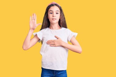 Cute hispanic child girl wearing casual white tshirt swearing with hand on chest and open palm, making a loyalty promise oath 