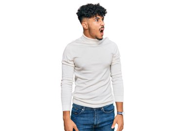 Genç Arap adam, günlük kazak giyiyor kızgın ve kızgın bağırıyor sinirli ve öfkeli, öfkeyle bağırıyor. öfke ve agresif konsept. 