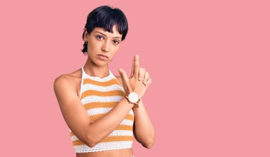 Kısa saçlı genç esmer kadın gündelik kıyafetler giyiyor. Sembolik bir silah tutuyor. El hareketleriyle cinayet silahlarıyla oynuyor. 