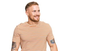 Sıradan kıyafetler giyen genç İrlandalı adam yüzünde gülümsemeyle yan yana bakıyor, doğal bir ifade. Kendinden emin gülen. 