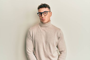 Yakışıklı genç adam sıradan bir süveter giyer ve altı numaralı parmaklarıyla işaret ederken kendinden emin ve mutlu bir şekilde gülümser.. 