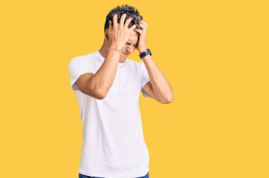 Genç, yakışıklı bir adam günlük beyaz tişört giyiyor. Baş ağrısı çekiyor. Acı ve migren yüzünden çaresiz ve stresli. Eller başının üstünde.. 