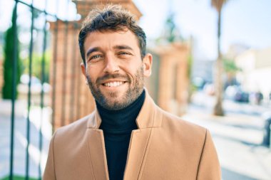 Zarif ceket giyen yakışıklı iş adamı dışarıda mutlu bir şekilde gülümsüyor.