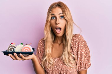 Güzel sarışın kadın elinde pasta tatlısı tutuyordu. Korkmuş ve şaşırmış bir şekilde ağzı açık, şaşırmış bir halde. 