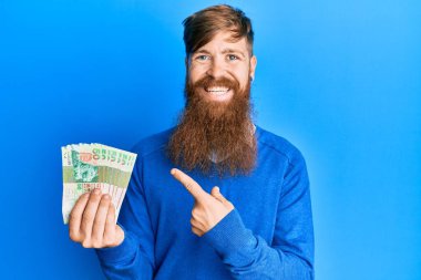 Genç İrlandalı kızıl adam Hong Kong 'u tutuyor 50 dolarlık banknotlar mutlu bir şekilde el ve parmak işareti yapıyor. 