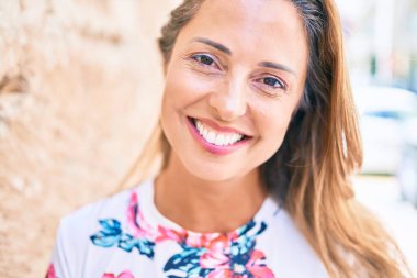 Genç İspanyol kadın gülümseyerek şehirde mutlu mesut duruyor.