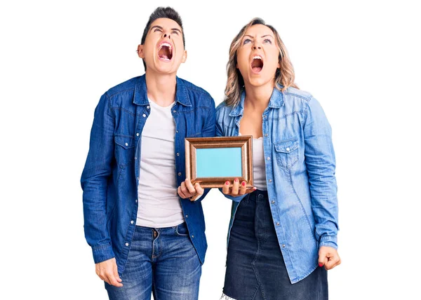 Couple Women Holding Empty Frame Angry Mad Screaming Frustrated Furious — Stock Photo, Image