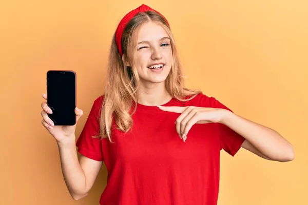 Beautiful Young Caucasian Girl Holding Smartphone Showing Screen Winking Looking — Stockfoto