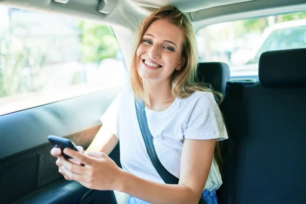 Νεαρή Όμορφη Ξανθιά Γυναίκα Χαμογελώντας Ευτυχισμένη Κάθεται Στο Αυτοκίνητο Χρησιμοποιώντας — Φωτογραφία Αρχείου