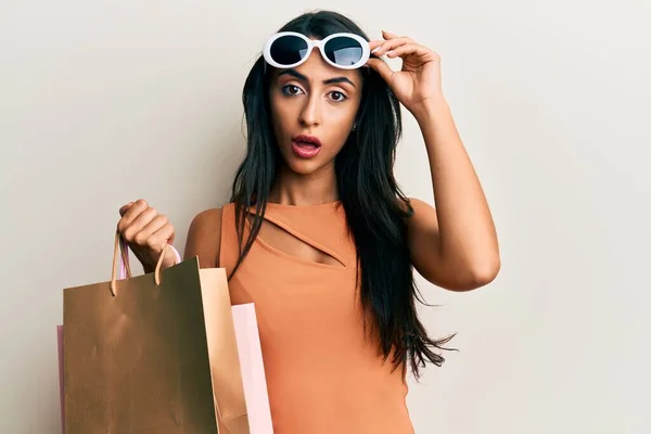 Beautiful Hispanic Woman Holding Shopping Bags Wearing Sunglasses Shock Face — Stock fotografie
