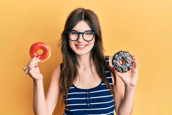 Joven Hermosa Chica Caucásica Sosteniendo Sabrosas Rosquillas Coloridas Sonriendo Con —  Fotos de Stock