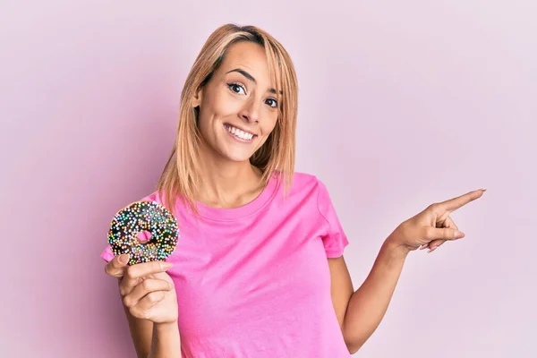 도넛을 행복하게 손가락으로 가리키는 아름다운 — 스톡 사진