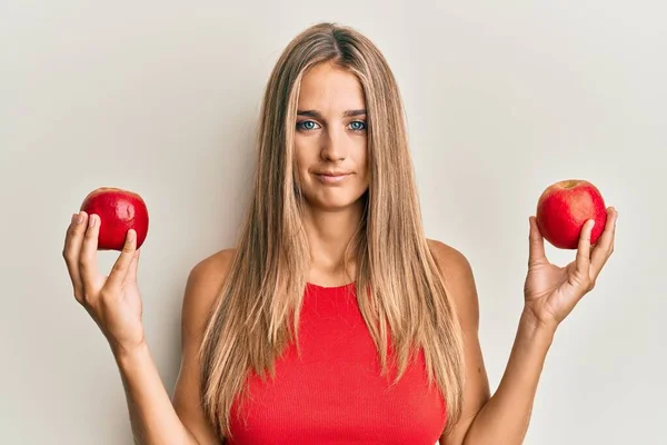 Νεαρή Ξανθιά Γυναίκα Που Κρατάει Κόκκινα Μήλα Χαλαρά Σοβαρή Έκφραση — Φωτογραφία Αρχείου