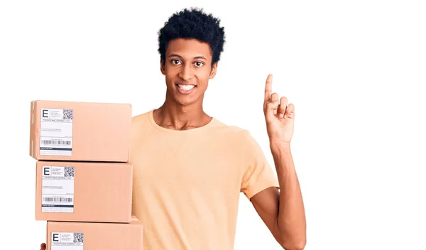 Young African American Man Holding Delivery Package Surprised Idea Question — Stock Photo, Image