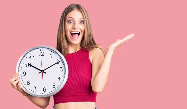 Young Beautiful Blonde Woman Holding Big Clock Celebrating Victory Happy — Stok fotoğraf