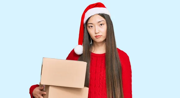 Jovem Chinesa Vestindo Chapéu Natal Segurando Pacote Entrega Pensando Atitude — Fotografia de Stock