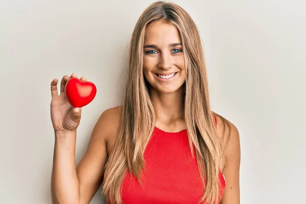 Giovane Donna Bionda Che Tiene Cuore Guardando Positivo Felice Piedi — Foto Stock