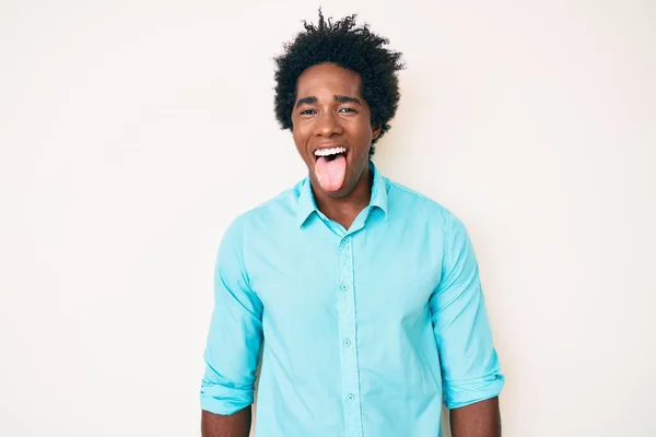 アフロの髪をしたハンサムなアフリカ系アメリカ人男性が面白い表情で舌を突き出してカジュアルな服を着ています 感情の概念 — ストック写真