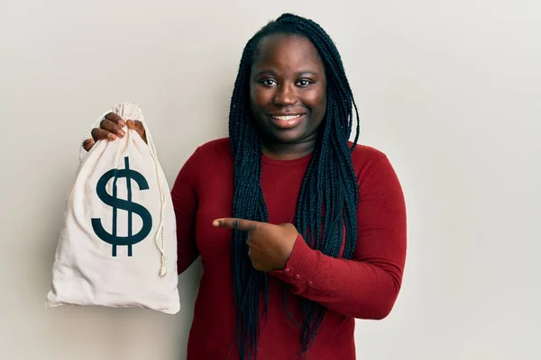 Mladá Černošky Žena Copánky Držení Dolarů Taška Úsměvem Šťastný Ukazující — Stock fotografie