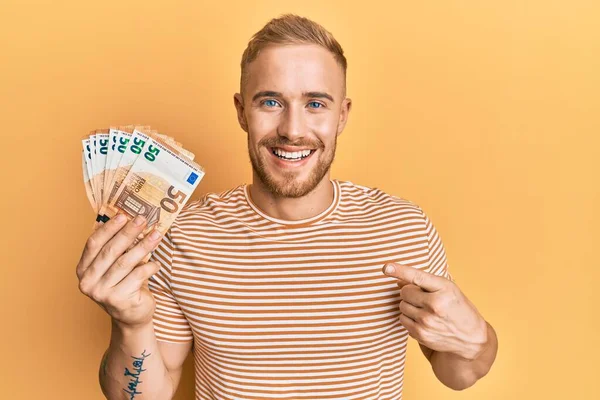 Joven Hombre Caucásico Sosteniendo Manojo Billetes Euros Sonriendo Feliz Señalando —  Fotos de Stock