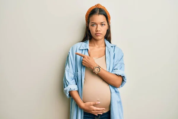Beautiful Hispanic Woman Expecting Baby Touching Pregnant Belly Pointing Hand — Stockfoto
