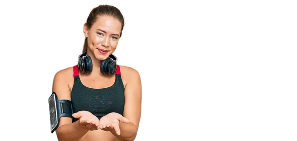 Hermosa Mujer Rubia Vistiendo Ropa Gimnasio Usando Auriculares Sonriendo Con —  Fotos de Stock