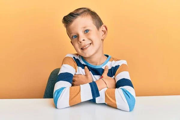 Roztomilé Bělošské Dítě Neformálním Oblečení Sedící Stole Šťastné Tváře Usmívající — Stock fotografie