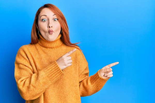 Beautiful Redhead Woman Pointing Fingers Side Making Fish Face Mouth — Stock fotografie