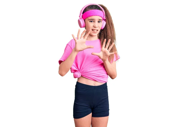 Cute Hispanic Child Girl Wearing Gym Clothes Using Headphones Disgusted — Fotografia de Stock