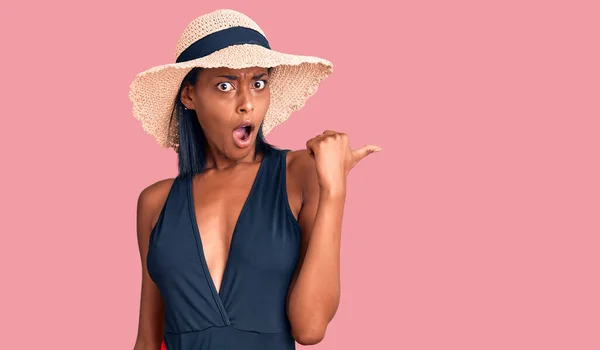 Young African American Woman Wearing Swimsuit Summer Hat Surprised Pointing — Stock fotografie