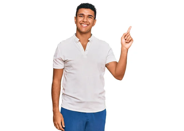 年轻的阿拉伯男子身穿休闲装 脸上挂着大大的笑容 手指头指向侧面看相机 — 图库照片