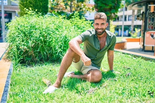 Joven Hombre Hispano Sonriendo Feliz Sentado Hierba Parque —  Fotos de Stock