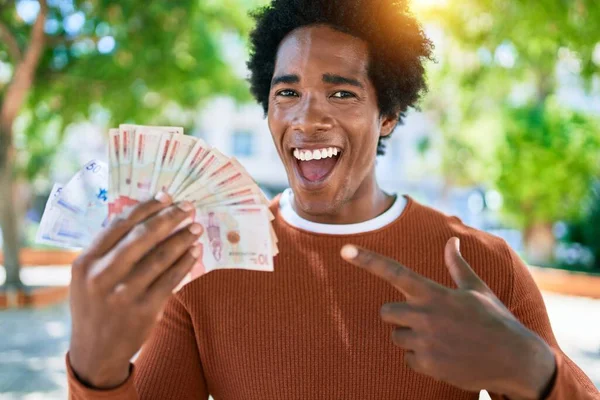 年轻的非洲裔美国人开心地笑着 站在街上 脸上挂着笑容 手里拿着科洛姆比亚比索钞票 — 图库照片
