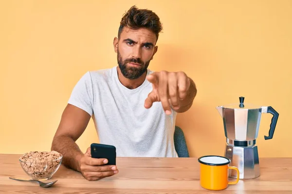 Joven Hombre Hispano Sentado Mesa Desayunando Usando Smartphone Apuntando Con — Foto de Stock