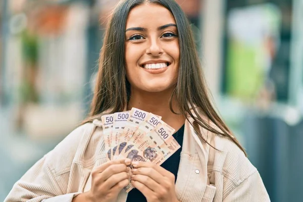 年轻的惊慌失措的姑娘高兴地微笑着 在城里拿着500比索钞票 — 图库照片